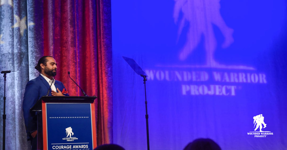 Wounded Warrior Project representative speaking with students during a Veterans Day assembly.