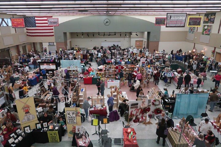 Visitors browse artisan booths at a bustling fall craft show, featuring handmade goods and local vendors.